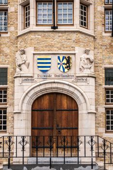 Diksmuide, Flanders, Belgium -  June 19, 2019: Grote Markt. monumental entrance to city hall or stadhuis with dark brown wooden doors and sculptures set on top with coat of arms.