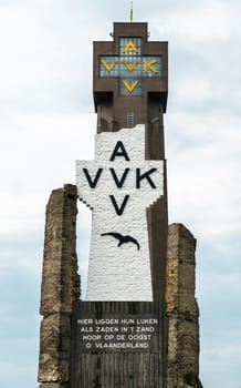 Diksmuide, Flanders, Belgium -  June 19, 2019: Black on White Crypt memorial, remnants of dynamited tower, and top of new IJzertoren, tallest peace monument of WW 1 against gray cloudscape.