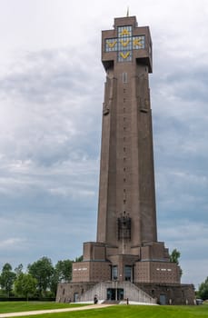 Diksmuide, Flanders, Belgium -  June 19, 2019: IJzertoren, tallest peace monument of WW 1 against gray blue cloudscape. On wall saying No More War. Some green foliage and lawn.
