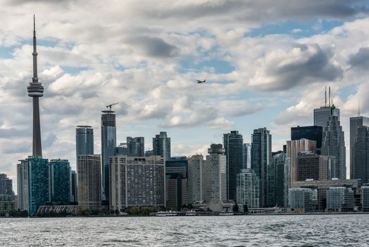 A small airplane flies above the skyscrapers and television tower of Old Toronto. View from Algonquin island, Canada