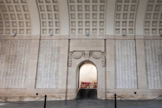 Diksmuide, Flanders, Belgium -  June 19, 2019: Historic Menin Gate. Main thoroughfare showing one beige wall with names, vaulted roof, and steps up to wreaths with red poppies.