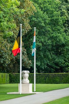Diksmuide, Flanders, Belgium -  June 19, 2019: Historic Menin Gate. Honoring statue for Indian Commonwealth soldiers killed during WW1. Indian and Belgian flag. Green foliage.