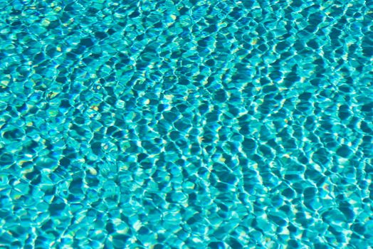 Close view of turquoise water surface full of ripples, waves and light spots