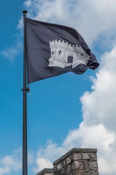 Gent, Flanders, Belgium -  June 21, 2019: Closeup of black-white flag of Gravensteen on top of castle tower against white cloudscape with blue patches.