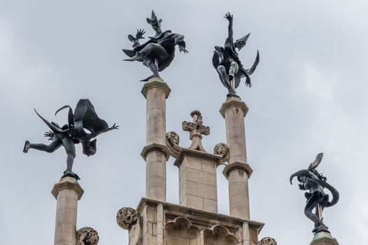 Gent, Flanders, Belgium -  June 21, 2019: Closeup of Dark Bronze Four dancers statue on beige gable top of Metselaarshuis, Masons Guild House against light blue sky.