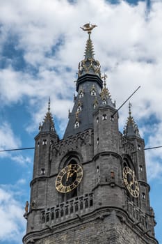 Gent, Flanders, Belgium -  June 21, 2019: Highest section of Belfry clock tower with Gulden Draak dragon statue against blue sky with white clouds.