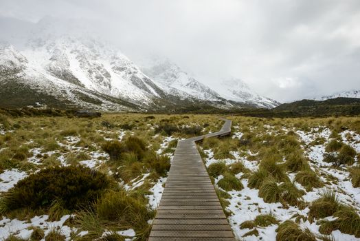 Curvy hanging wooden pathway protects highland snowy mountain ecosystem at Hooker Valley Track