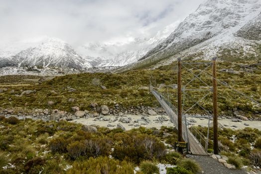 Snowy mountain scenery with scary hanging bridge at Hooker Valley Track, Mount Cook National Park, New Zealand