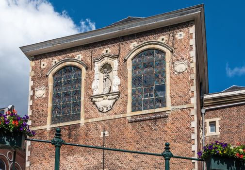 Gent, Flanders, Belgium -  June 21, 2019: Red brick facade with centrally place white Madonna statue of Saint Augustine cloister under blue sky along Lieve River.