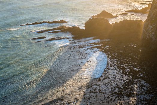 Sunset view of the Pacific Ocean coast, waves and cliffs at Nugget Point, New Zealand