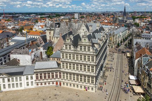 Gent, Flanders, Belgium -  June 21, 2019: Shot from top Belfry. Historic city or town hall in middle of cityscape of buildings and roofs stretching to flat horizon. Blue cloudscape.