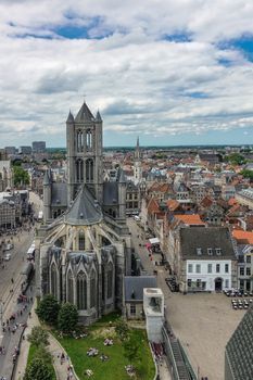 Gent, Flanders, Belgium -  June 21, 2019: Shot from top Belfry. Sint Niklaas Church in middle of cityscape of buildings and roofs stretching to flat horizon. Blue cloudscape.