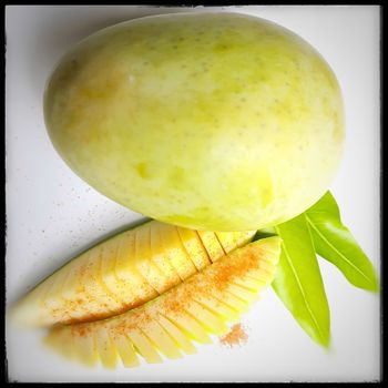 One mango and its slices of mango beautifully arranged in white plate with its leaf nd summer fruit and good for health also