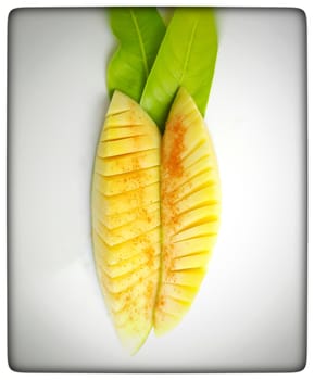 Pieces of mango cut beautifully like slant and box slices arranged in white plate with its leaf nd summer fruit and good for health also