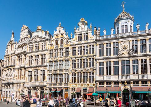Brussels, Belgium - June 22, 2019: Beige stone facades and gables with statues on top and bar-restaurants on ground at northwest side of grand Place. People.