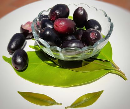 Black plum in bowl decorated beautifully with its leaves contains vitamin C and iron hemoglobin heart healthy and treats diabetes summer season fruit