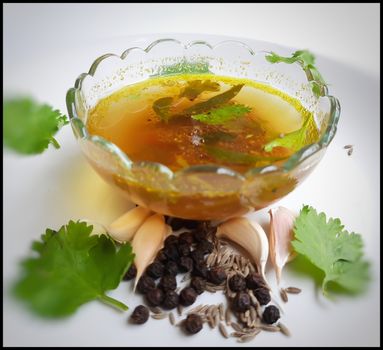 indian traditional food tomato pepper soup in bowl with its spices pepper cumin garlic beautifully kept in white plate