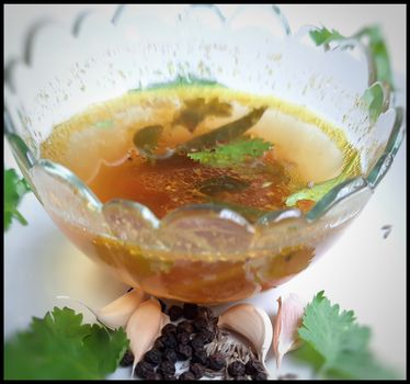 indian traditional food tomato pepper soup in bowl with its spices pepper cumin garlic beautifully kept in white plate