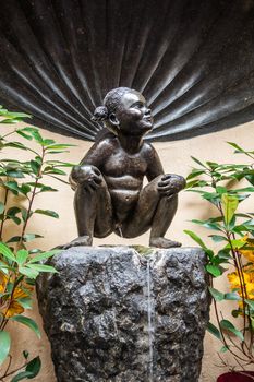 Brussels, Belgium - June 22, 2019: Closeup of iconic and original Jeanneke Pis statue, urinating on black rock.