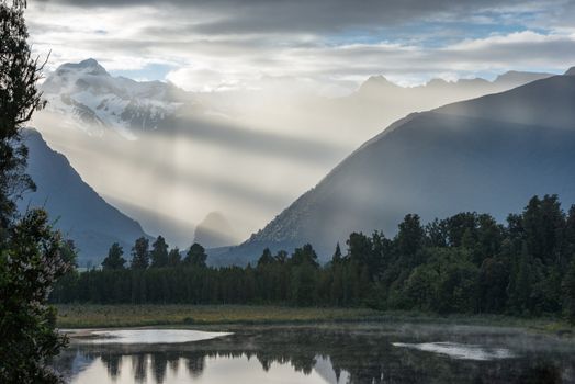 Bright contrast rays of morning sun over the Lake Matheson, New Zealand