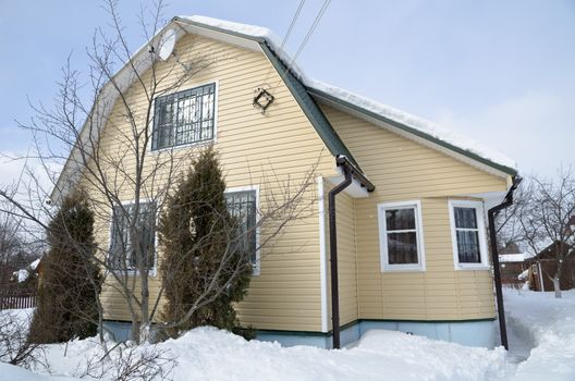 Beautiful winter view of the cottage and frozen trees under the blue sky