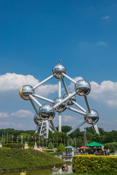 Brussels, Belgium - June 22, 2019: Atomium monument with its silver balls and pipes against blue sky with white cloudscape seen from mini-Europe park.