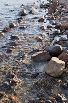 Small stones and rocks at the edge of the sea and in the waves