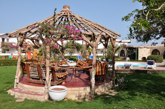 Relaxing picture of the cold hotel swimming pool with clear water and some chairs, trees and lounges around