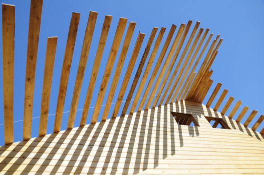 The unfinished wooden roof and empty windows at the blue sky background