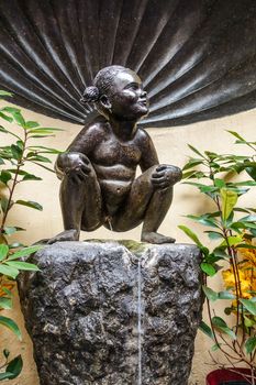Brussels, Belgium - June 22, 2019: Closeup of iconic and original Jeanneke Pis statue, urinating on black rock.