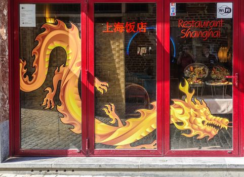 Brussels, Belgium - June 22, 2019: Closeup of red framed window with golden dragon painting of Shanghai Restaurant,