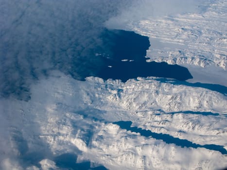 Aerial view of the Greenland coastline with mountain, ocean and clouds