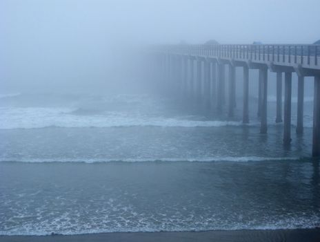 Ocean pier, vanishing in the mist and ocean waves at Sun Diego, USA