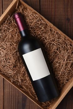 Cabernet Wine Bottle in Packing Straw: High angle shot of a single bottle with blank label in a cardboard box with straw packing.