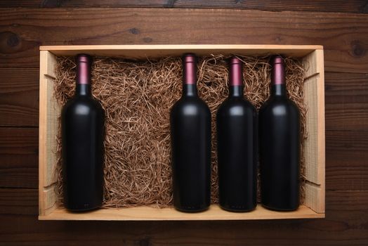 Case of Red Wine: Top view of a wood case of red wine bottles with one bottle missing, the case is filled with packing straw.