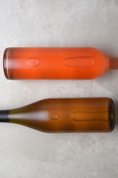 Chardonnay and Blush Wine Bottles: Two bottles on a concrete table top with copy space at the top and bottom of the frame.