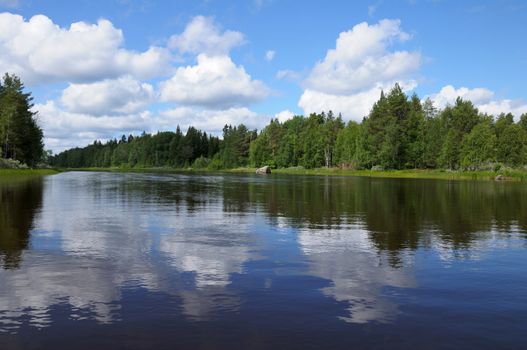 The beautiful picture of Karelian forest at the edge of a lake, and some huge boulder in this lake