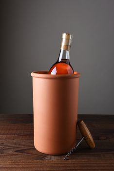 Terra cotta wine chiller on a rustic wood table.