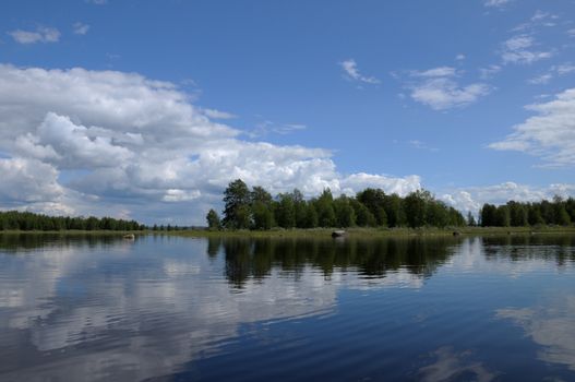 The beautiful picture of Karelian forest at the edge of a lake, and some huge boulder in this lake