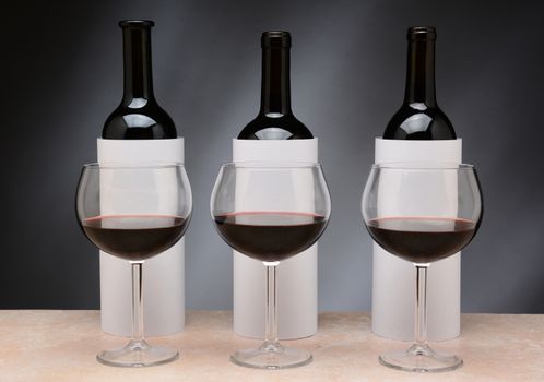 Three different wine bottles set up for a blind wine tasting. The bottles are covered by blank cylinders to hide the label. Horizontal format.