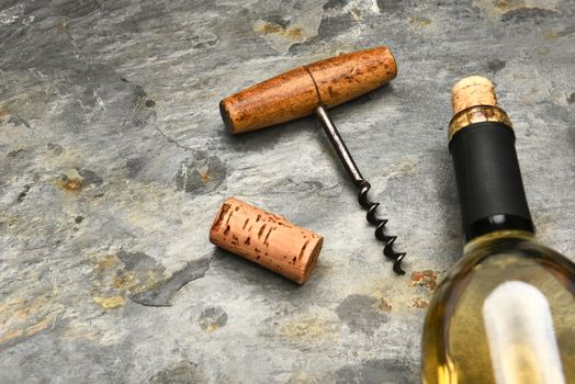 Top view of a wine bottle and cork screw on a slate surface. 