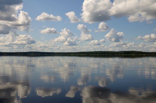 The picture shows typical landscape in the south region of Karelia - blue sky, clouds, big lake looks like a mirror and a lot of distant green islands, trees, stones and rocks