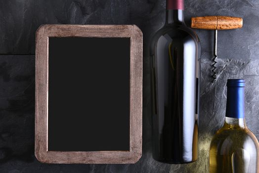 Top view of two wine bottles and corkscrew next to a blank chalk board wine list.
