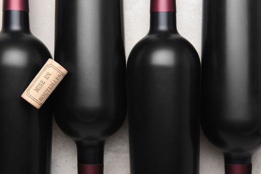 Closeup of four red wine bottles and cork with the French words Mis en Bouteilles, English translation is - bottled at the estate.