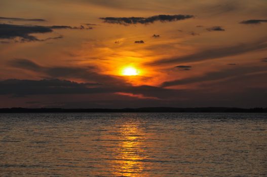 The final stage of a cloudy sunset above the huge lake in Karelia region. The picture is colorful and relaxing.