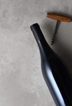 Flay lay arrangement of a wine bottle and corkscrew with copy space. The Pinot Noir shaped bottle has no label.