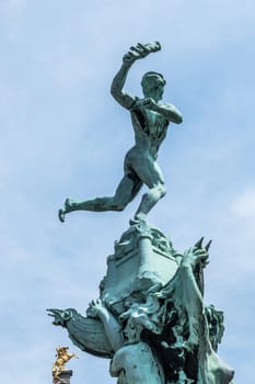 Antwerpen, Belgium - June 23, 2019: Top of Green bronze Brabo statue on Grote Markt under blue sky. Golden Horse of gable in back.