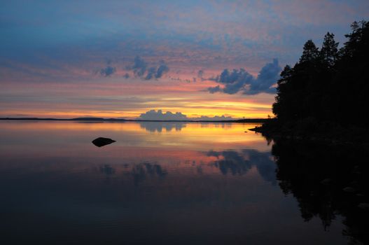 The final stage of a cloudy sunset above the huge lake in Karelia region. The picture is colorful and relaxing.