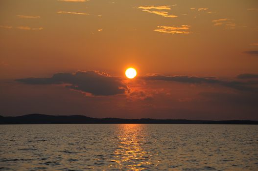 The final stage of a cloudy sunset above the huge lake in Karelia region. The picture is colorful and relaxing.