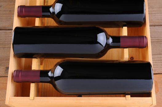 Three red wine bottles in a wooden case, isolated on white, Vertical Format.